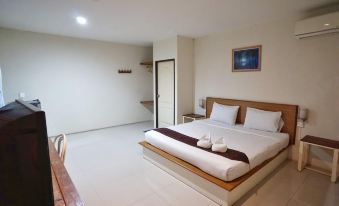 a modern bedroom with white walls , wooden furniture , and a bed with multiple pillows , as well as a staircase leading to another room at Tonnam Resort