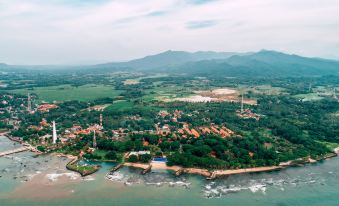 aerial view of a small town by the water , surrounded by green fields and mountains at Mambruk Hotel & Convention