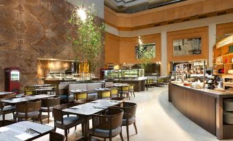 a restaurant with tables and chairs in the center, as well as additional seating areas for customers at Sheraton Grand Taipei Hotel