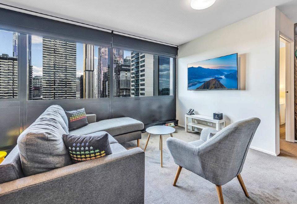 a modern living room with a large window , gray and white furniture , and a blue ocean painting on the wall at Pegasus Apart'Hotel