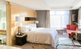 A bedroom with large windows, a bed, and a desk in the middle is located next to another room at The Westin Bund Center Shanghai