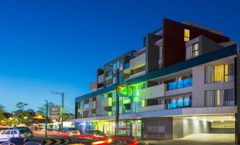 a modern building with multiple floors , lit up at night , and red and yellow traffic lights , creating a lively atmosphere at Quest Cheltenham