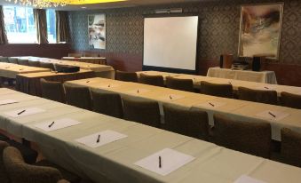 There is a spacious conference room arranged with long tables and chairs for hosting events or presentations at Ramada Grand Tsim Sha Tsui