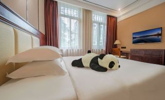 a hotel room with two beds , one on the left and one on the right , both adorned with stuffed pandas at Panda Hotel