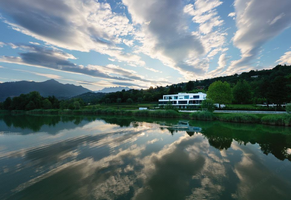 a white house is reflected in a pond with mountains in the background , creating a serene atmosphere at Bianca Relais