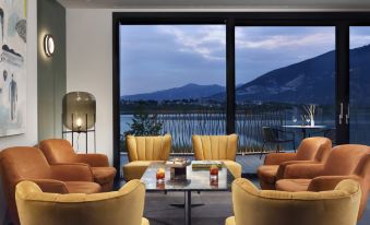 a modern living room with a large window offering a view of the lake and mountains , featuring comfortable seating arrangements and a glass coffee table at Bianca Relais