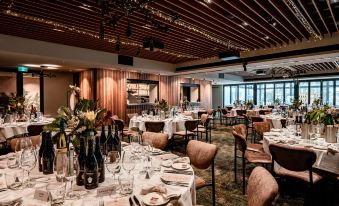 a large dining room with multiple tables set for a formal event , featuring wine glasses and bottles on the table at Marion Hotel