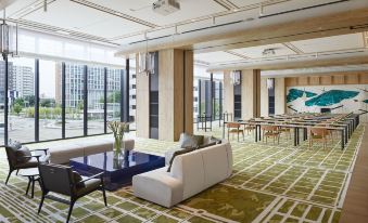 The spacious room features comfortable seating areas and tables in the center, with large windows offering a stunning city view at Hyatt Centric Kanazawa