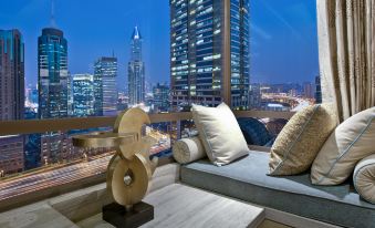 The living room is furnished with a balcony featuring large windows that overlook the city and other buildings at Kempinski The One Suites Hotel Shanghai Downtown