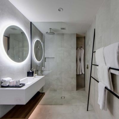 a modern bathroom with a large mirror , white walls , and a walk - in shower area at Oval Hotel at Adelaide Oval, an EVT hotel