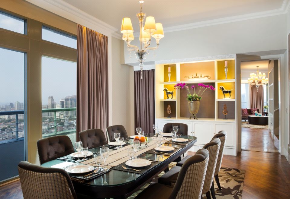 a dining table is set with plates , glasses , and silverware in a room with large windows at Ascott Jakarta