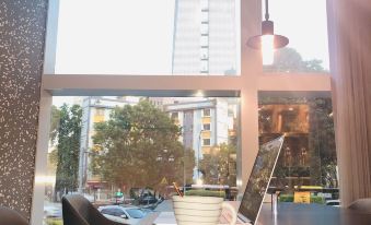 There is a table and chairs positioned in front of a window in an office that has large windows providing a view of other areas at Insio Hotel (Shenzhen Shekou Maritime World)