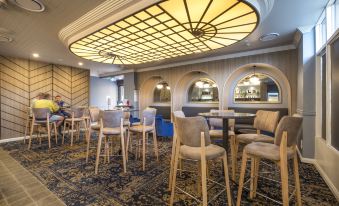 a dining room with a round table surrounded by chairs , and a bar in the background at Nightcap at Pymble Hotel