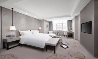 In a spacious, all-white bedroom, there is a large bed accompanied by two lamps and a side table at Byland Star Hotel (Yiwu International Trade City)