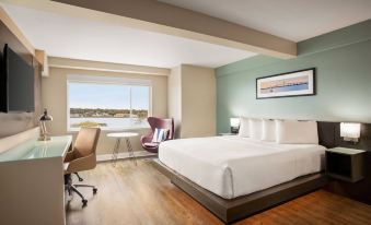 a modern hotel room with a large bed , wooden floors , and a view of the city at Wyndham Newport Hotel