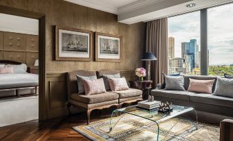 a living room with a brown couch , a coffee table , and a large window overlooking a city view at The Langham Melbourne