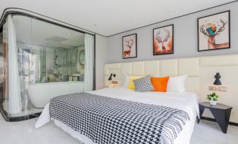 A large white bed is situated in a room that is predominantly glass and gray, adorned with pictures at Guangzhou Feiyang Apartment