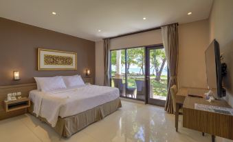 a luxurious hotel room with a king - sized bed , a desk , and a large window overlooking the ocean at Mambruk Hotel & Convention