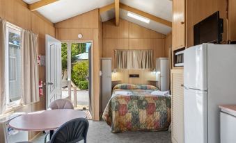 a small bedroom with a bed , a chair , a microwave , and a refrigerator in the room at Discovery Parks - Jindabyne
