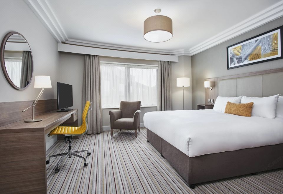 a modern hotel room with a bed , desk , chair , and window , decorated in neutral colors at Leonardo Hotel and Conference Venue Hinckley Island