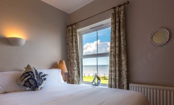 a bedroom with a large window overlooking the ocean , featuring a bed and white bedding at The Ship Inn