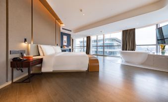 The modern bedroom features large windows, a white bed, and a wood-paneled accent wall at ATOUR HOTEL,Happy Avenue, Shunde OCT Harbour Branch, Foshan