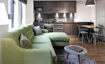 a modern living room with a green couch and a dining table in the background at Old Town Chambers, Autograph Collection