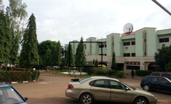 a parking lot with a car parked in front of a building , surrounded by trees at Marble Arch Hotels