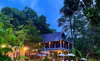 a large house surrounded by a lush green garden , with a table and chairs set up for outdoor dining at Proud Phu Fah Hip & Green Resort
