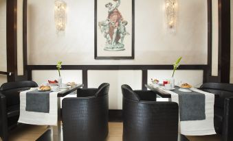 a restaurant with two dining tables , each set with black chairs and white tablecloths , next to framed art on the wall at Yes Hotel