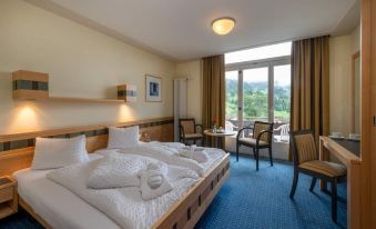 a hotel room with a large bed , two chairs , and a window overlooking a golf course at Arenas Resort Victoria-Lauberhorn
