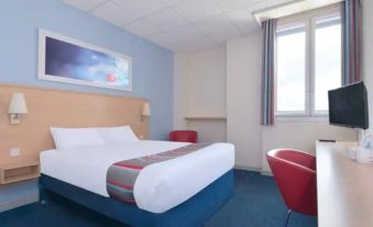 a hotel room with a blue and white color scheme , featuring a double bed and a chair at Travelodge St. Clears Carmarthen