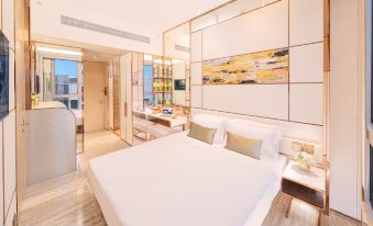 There is a large bed in a white room with wood paneling and a glass wall at Regala Skycity Hotel