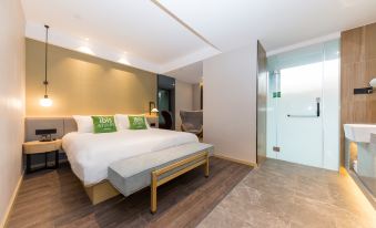 a modern bedroom with a large bed , wooden flooring , and a bathroom next to it at Ibis Styles Hotel