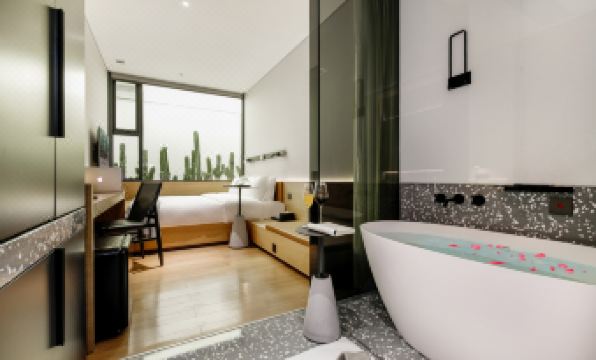 There is a modern bathroom with large windows, a bed, and a bathtub located in the middle room at Insio Hotel (Shenzhen Shekou Maritime World)