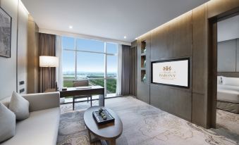 A modern living room with large windows and an entertainment center is also present at Grand Barony Qingdao Airport Hotel