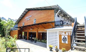 "a large wooden building with a sign that says "" toilet "" and other signage , surrounded by trees" at Bwalk Hotel Malang