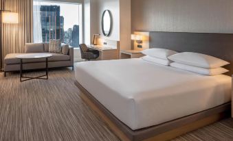 a hotel room with a large bed , a couch , a chair , and a tv . the room has a view of the city at Hyatt Regency Seattle