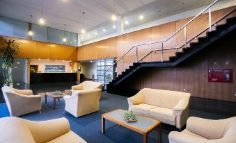 a modern living room with white furniture , blue carpet , and wooden walls , as well as a staircase leading to an upper level at Hotel Colombo