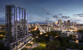 a city skyline at dusk , with tall buildings and a park visible in the foreground at The Milton Brisbane