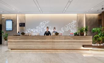 An employee is working at the front desk in the hotel lobby, with people on either side at OSK International Hotel