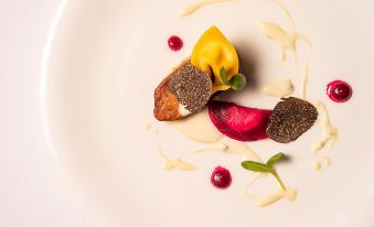 a white plate with a variety of food items , including sliced meat and vegetables , on it at Malibu Hotel