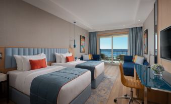 a hotel room with two beds , a desk , and a balcony view of the ocean at Rixos Water World Aktau