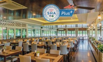 a large dining room with wooden tables and chairs arranged for a group of people to enjoy a meal together at Baan Amphawa Resort & Spa