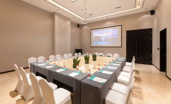 A spacious event room is arranged with long tables and chairs facing the front at JinHao YiMei Hotel