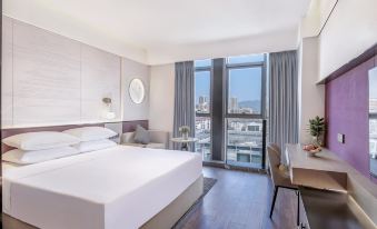 The modern bedroom features large windows, a white bed, and a table in the middle, providing a picturesque view of the city at Fuzhou Le'an New Century Mingting Hotel