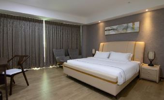 a large bed with white sheets and a beige headboard is in the middle of a room with gray curtains at Higher Hotel