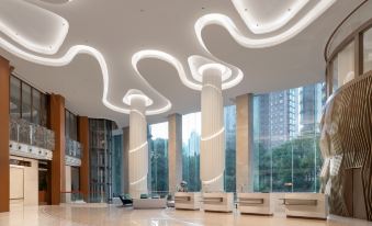 The lobby of this large hotel is adorned with a variety of unique lighting fixtures, creating a visually appealing atmosphere throughout the entire space at Pullman Shanghai Skyway Hotel
