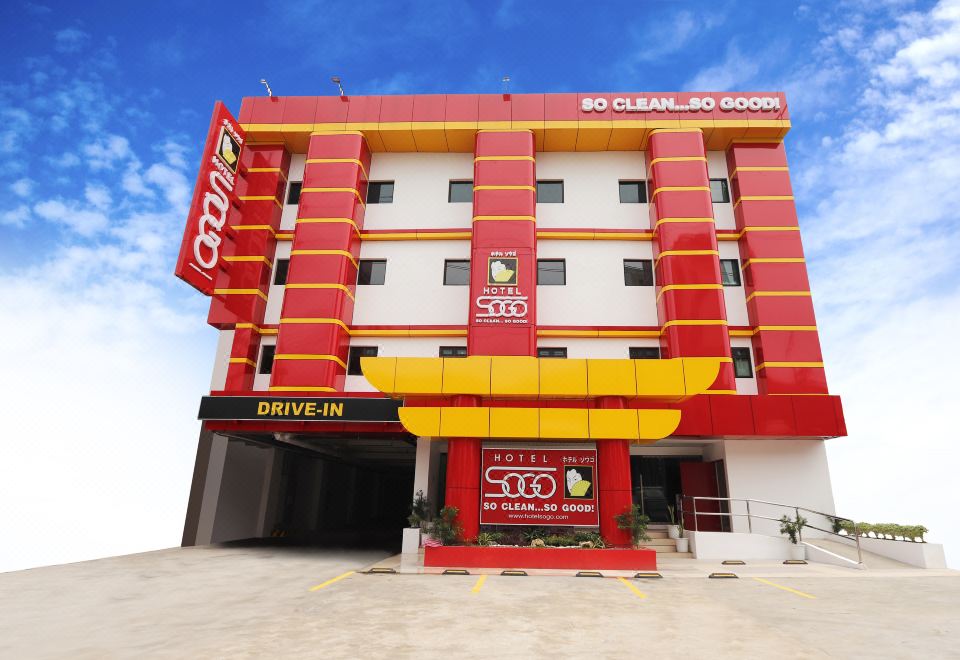 There is a hotel with two red and white signs on the side, and in front of it, there is an orange at Hotel Sogo Fairview