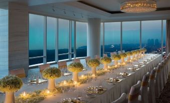 A table for two is set with large windows offering views of the city, while additional seating options are available at The Langham, Shenzhen